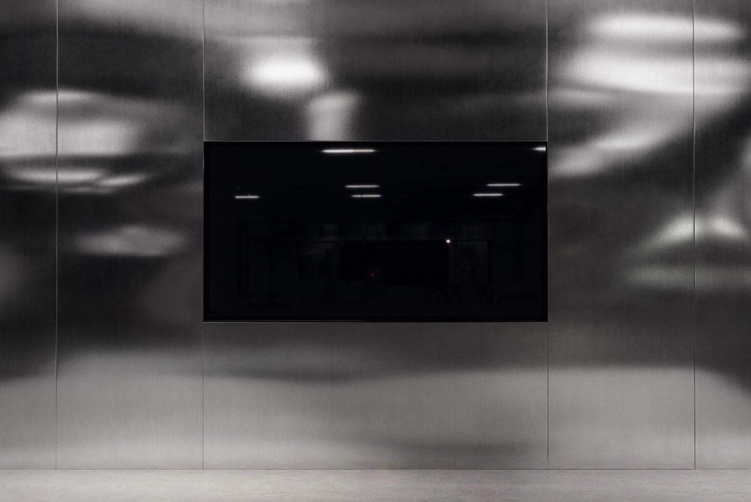 Black screen display mounted on blurred concrete wall in modern space