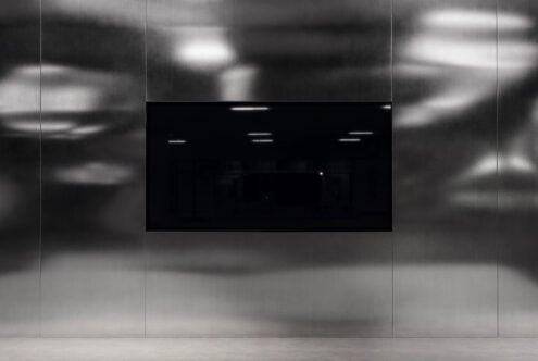 Modern industrial interior featuring a large black screen on a sleek metallic wall ideal for mockups or design presentations for digital designers.