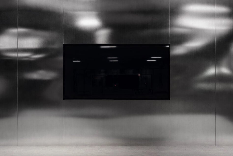 Black screen display mounted on blurred concrete wall in modern space