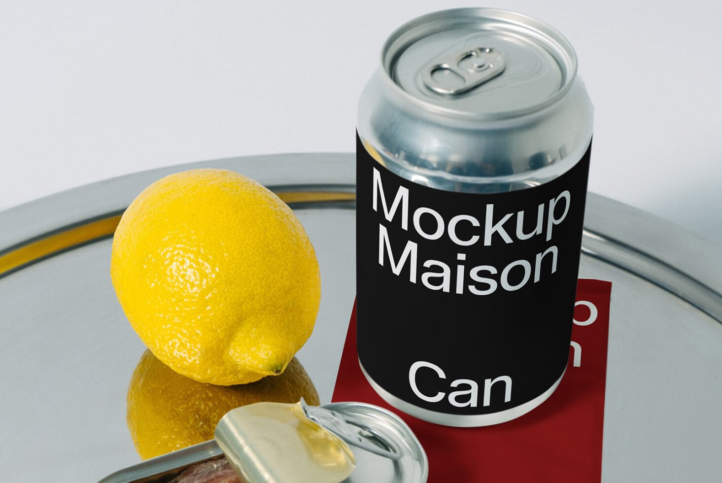 Sleek can mockup with bold black label design on silver surface, accompanied by a fresh lemon and tin opener, perfect for branding presentations.