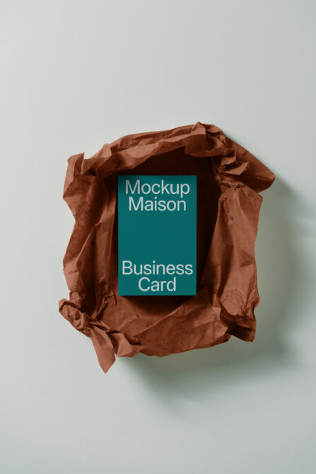 Teal business card stack wrapped in crumpled terracotta paper bag overhead shot
