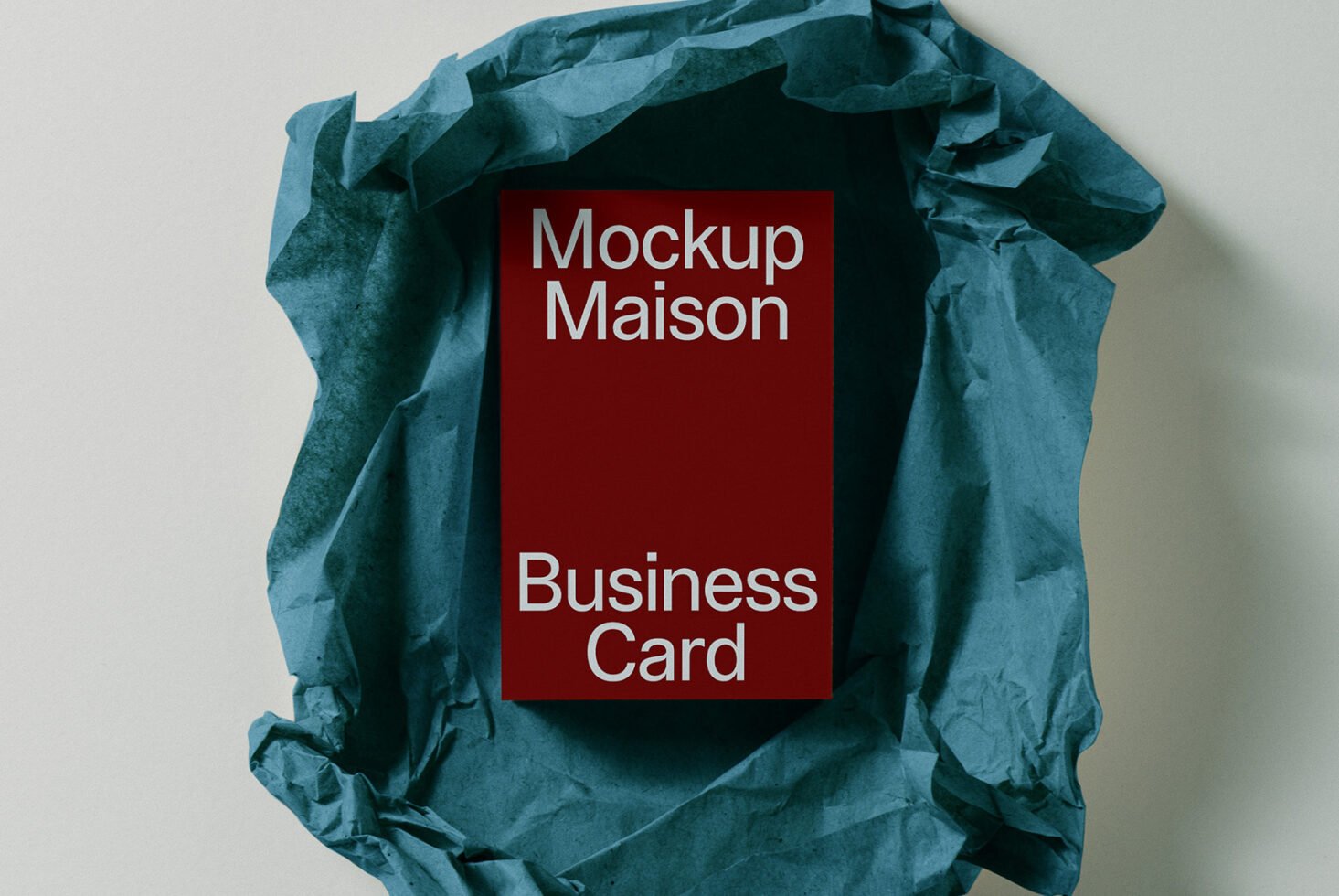 Business card mockup featuring a red card with white text placed on crumpled blue paper ideal for designers in need of professional templates