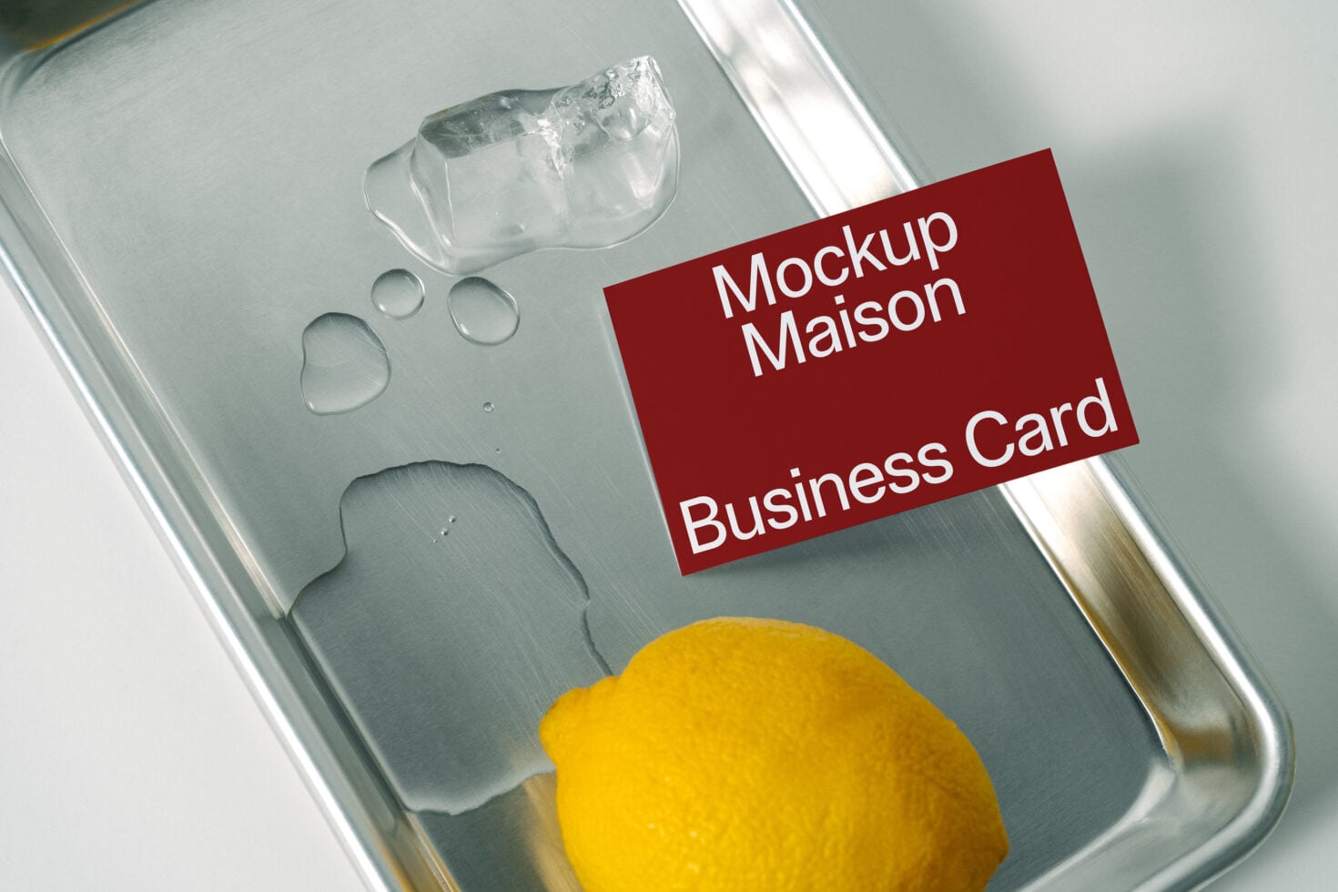Red business card on metal tray with water droplets beside yellow lemon