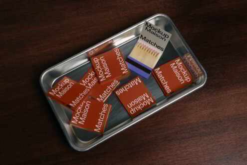 Matchbox mockup design on a metal tray with red matchbooks labeled Mockup Maison on wooden background perfect for branding templates and graphics.