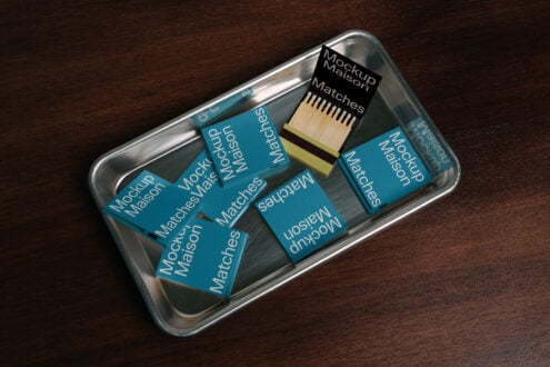 Blue matchboxes with text Mockup Maison in a metal tray on wooden surface. Ideal for showcasing design elements, mockups, templates for designers.