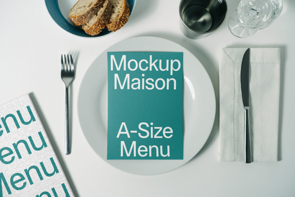 Teal A-size menu card on plate with place setting, bread, glasses nearby
