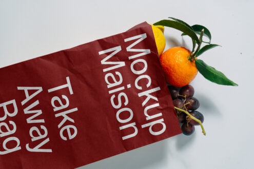 Eco-friendly takeaway bag mockup with fresh oranges and grapes emerging. Ideal for showcasing branding designs and packaging templates for designers.