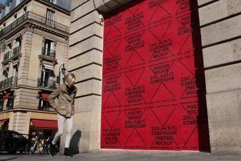 Urban poster mockup on red wall in city street scene featuring classic architecture; ideal for showcasing poster designs; template for designers; graphics.