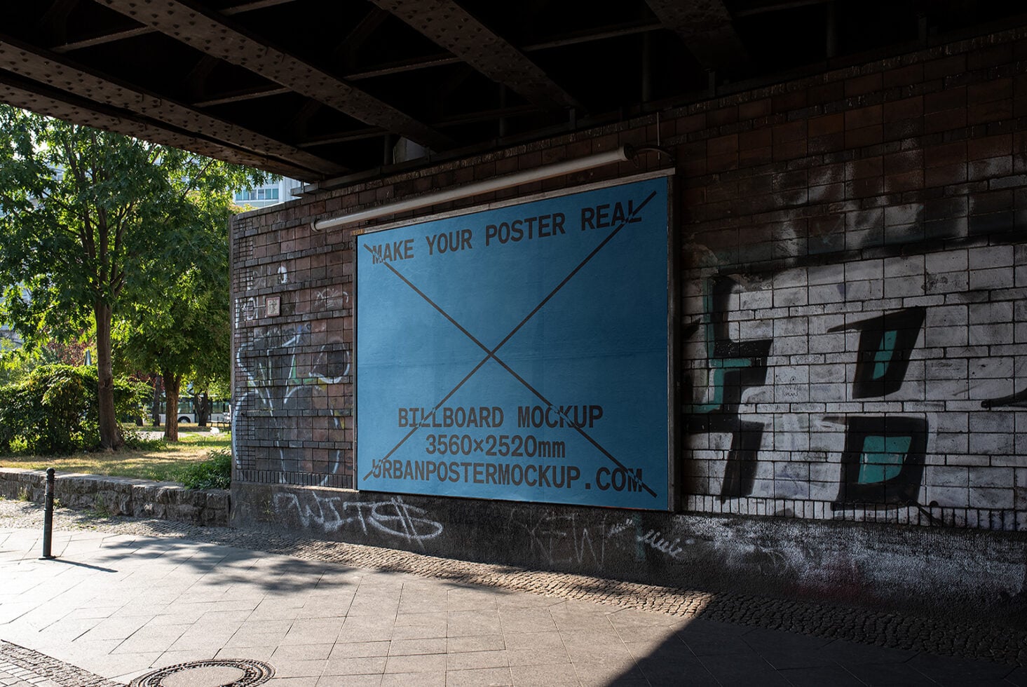 Blue billboard mockup mounted under bridge with green trees visible
