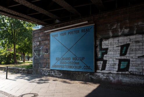 Urban billboard mockup on a brick wall under a bridge with graffiti in the background ideal for showcasing poster designs in a realistic street setting.