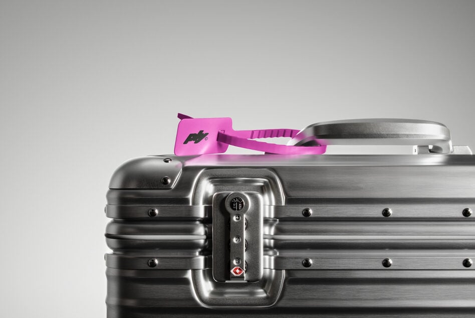 Silver metal suitcase with a pink luggage tag on top. Focus on lock and handle. Perfect for travel mockups and product design. High-quality image.