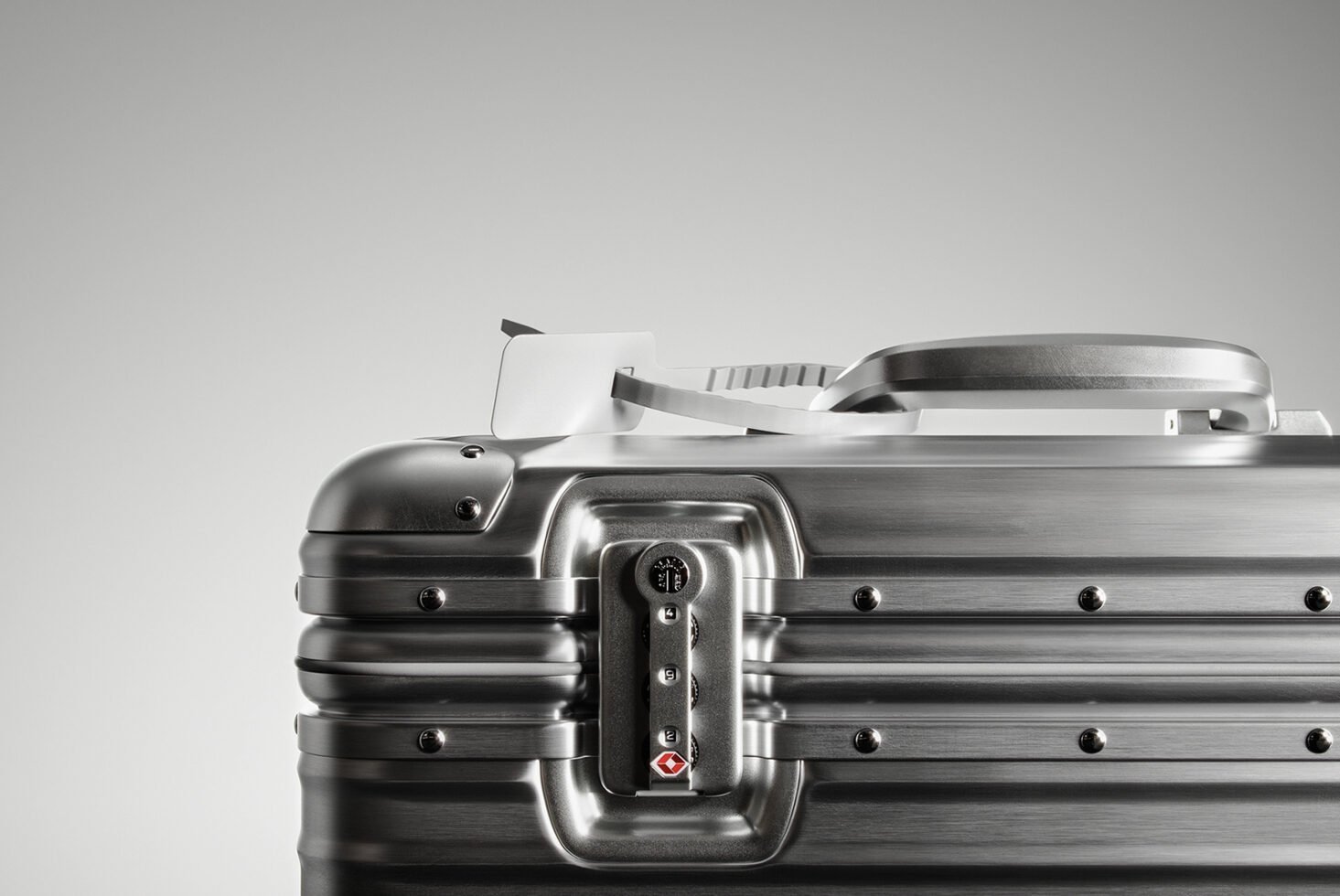 Metallic suitcase closeup with TSA lock and handle against grey background ideal for product design mockups digital asset for designers SEO friendly.