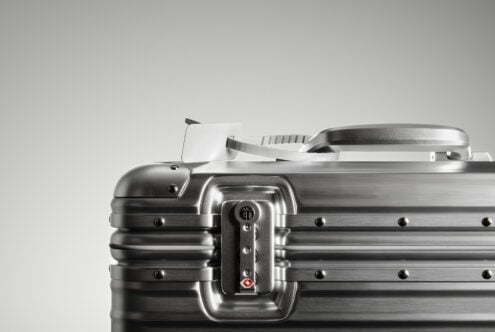 Metallic suitcase closeup with TSA lock and handle against grey background ideal for product design mockups digital asset for designers SEO friendly.