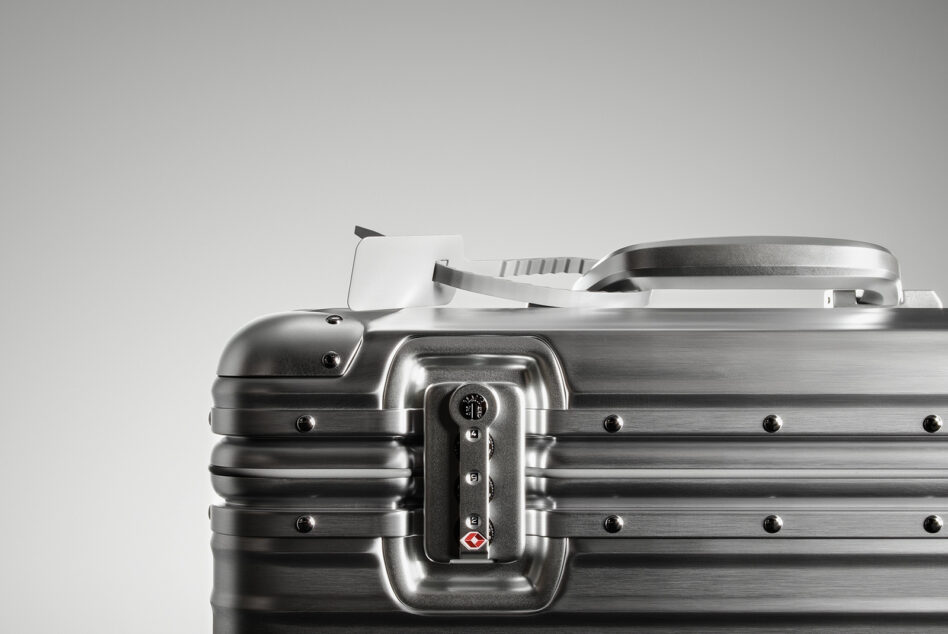 Metallic suitcase closeup with TSA lock and handle against grey background ideal for product design mockups digital asset for designers SEO friendly.