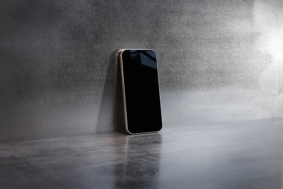 Smartphone with black screen leaning against concrete wall
