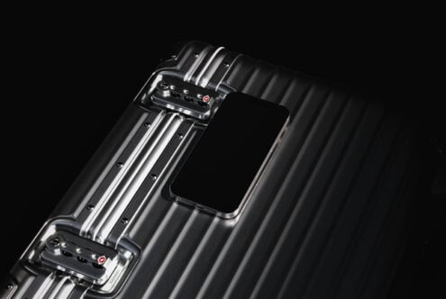 Sleek metal suitcase with phone resting on top. High-quality mockup for design projects. Keywords: suitcase mockup design phone showcase graphic resource.