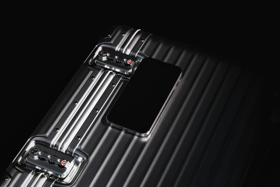 Sleek metal suitcase with phone resting on top. High-quality mockup for design projects. Keywords: suitcase mockup design phone showcase graphic resource.