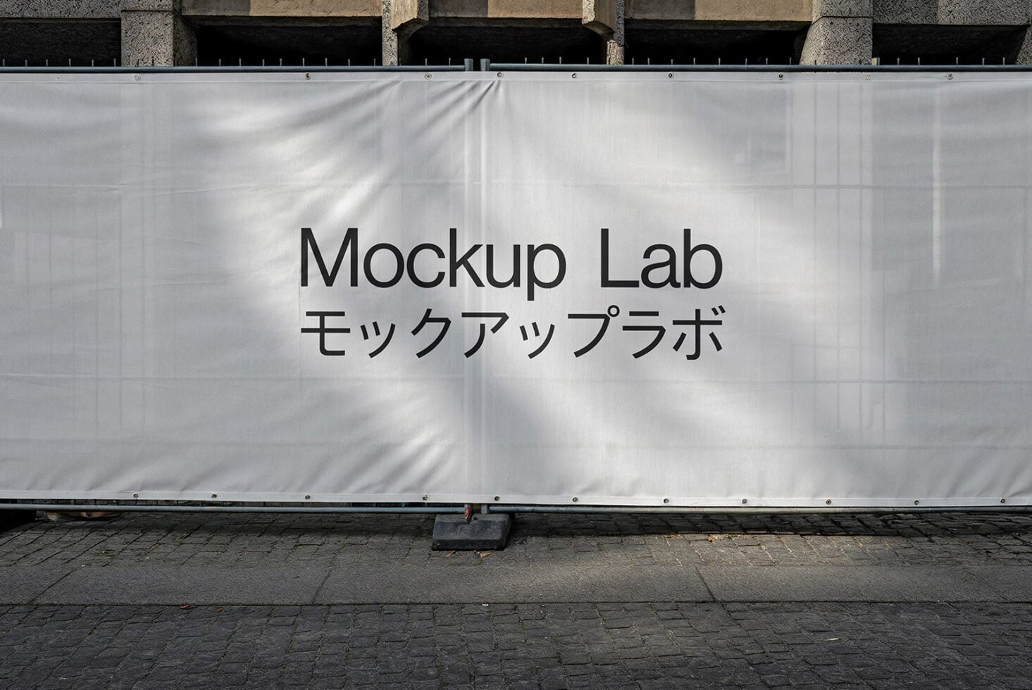 White construction mesh banner mockup on building facade with sunlight shadows