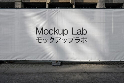 White construction mesh banner mockup on building facade with sunlight shadows