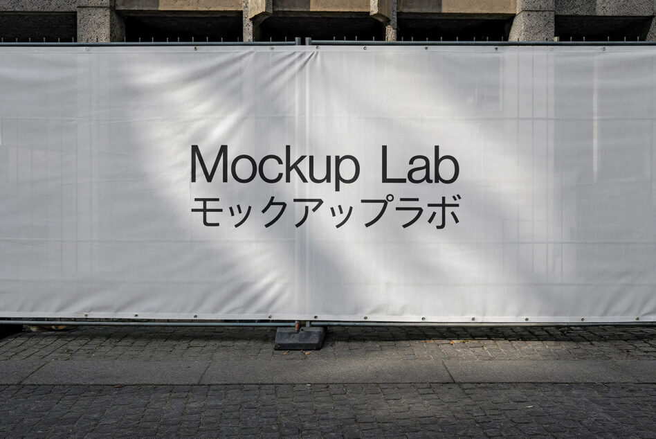 White construction mesh banner mockup on building facade with sunlight shadows