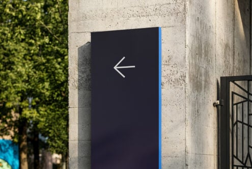 Navy blue panel with left arrow on concrete building exterior
