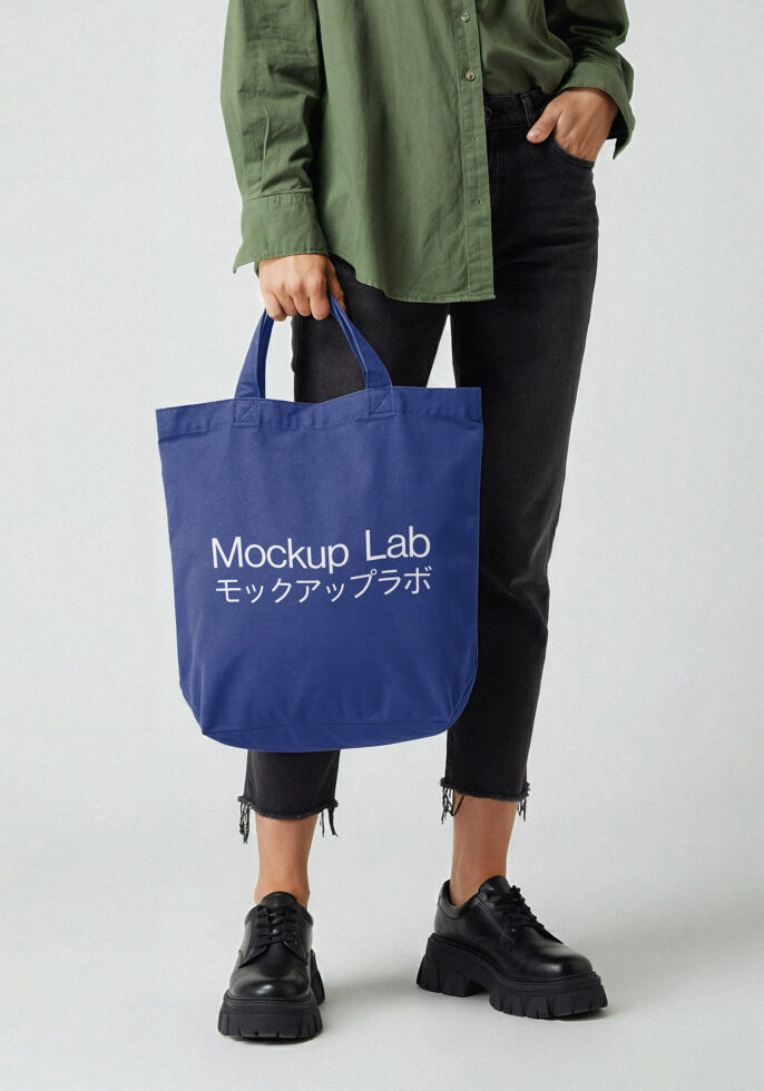 Person holding navy tote bag with Mockup Lab bilingual text in white