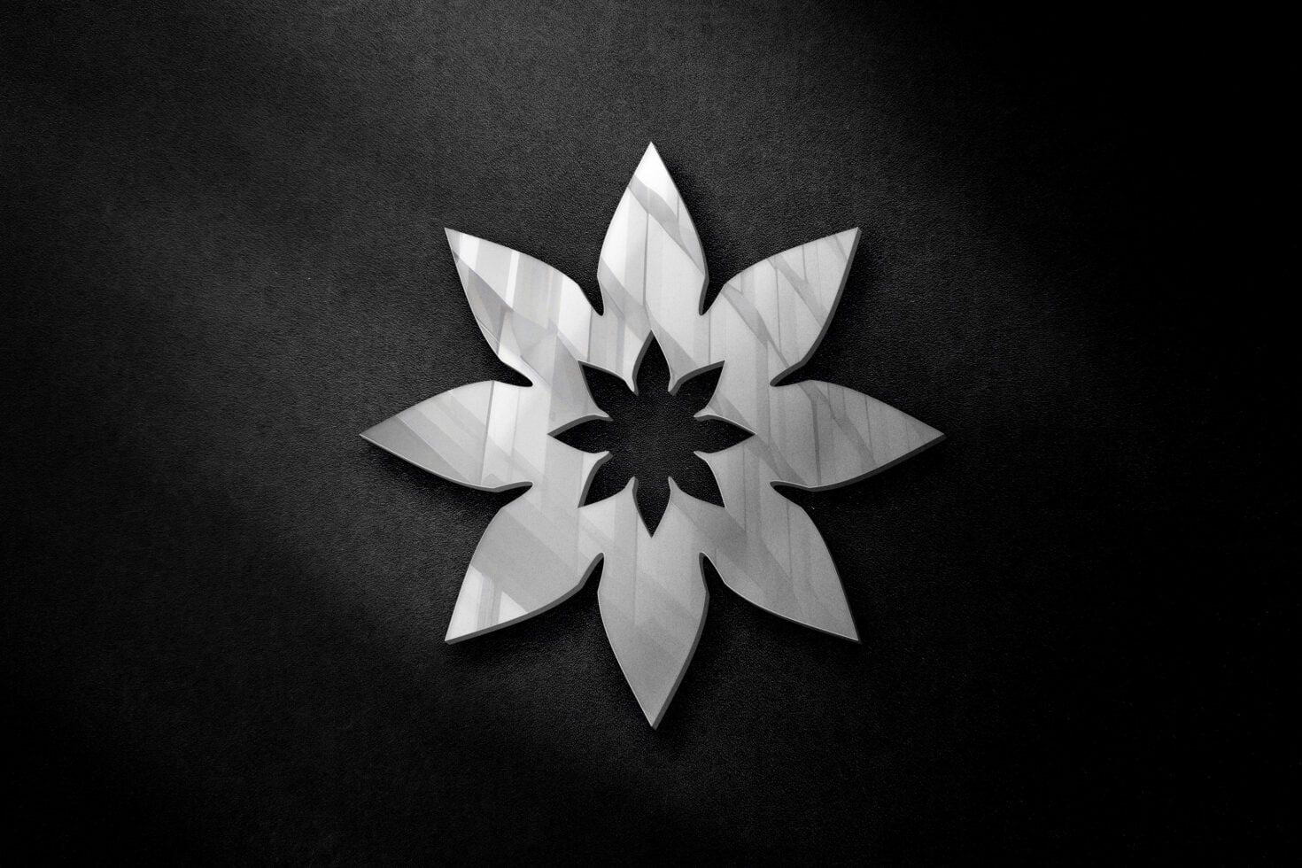 White geometric flower shape with layered petals on dark textured background