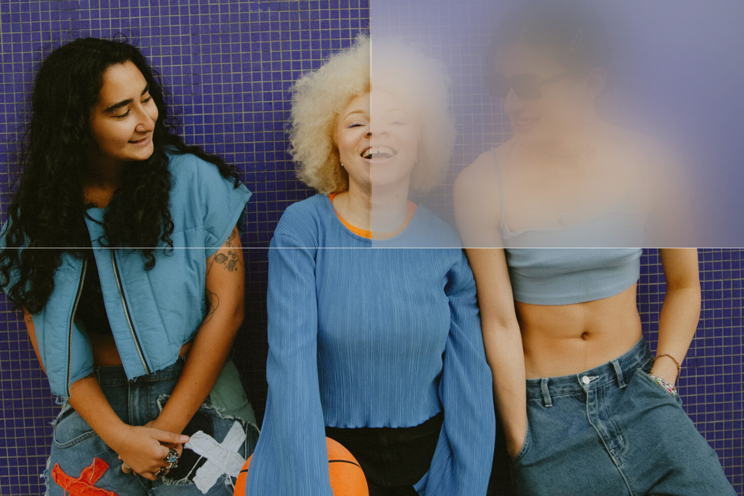 Three women laughing against purple tile wall with soft blur effect