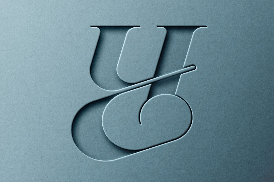 Carved serif letters spelling out on blue grey paper with dimensional cuts