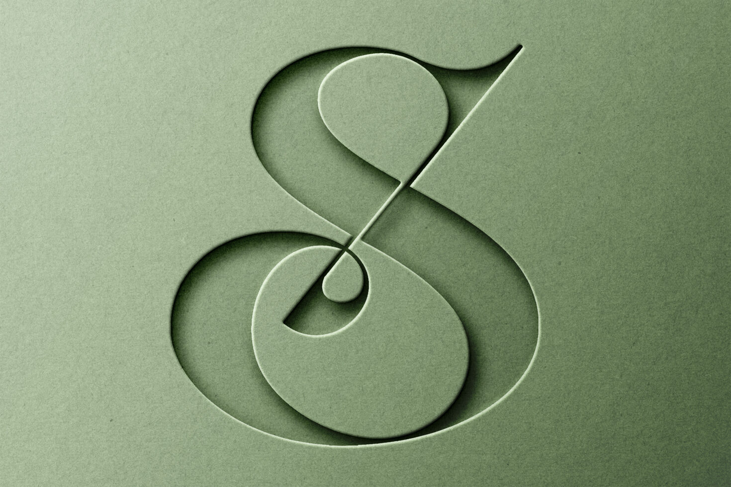 Minimal ampersand symbol carved with dimensional shadow into sage paper