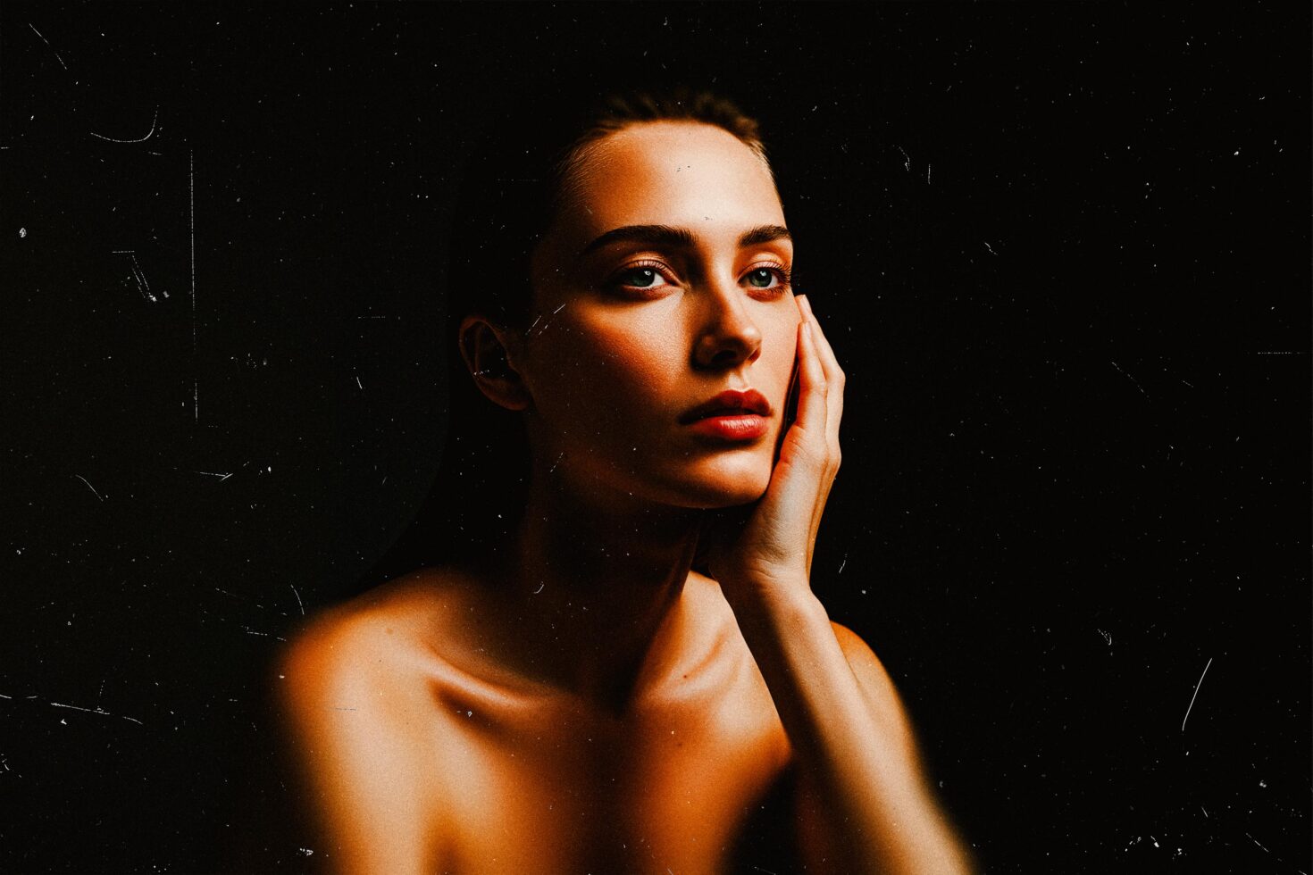 Woman's face with hand on cheek against black background with film grain texture