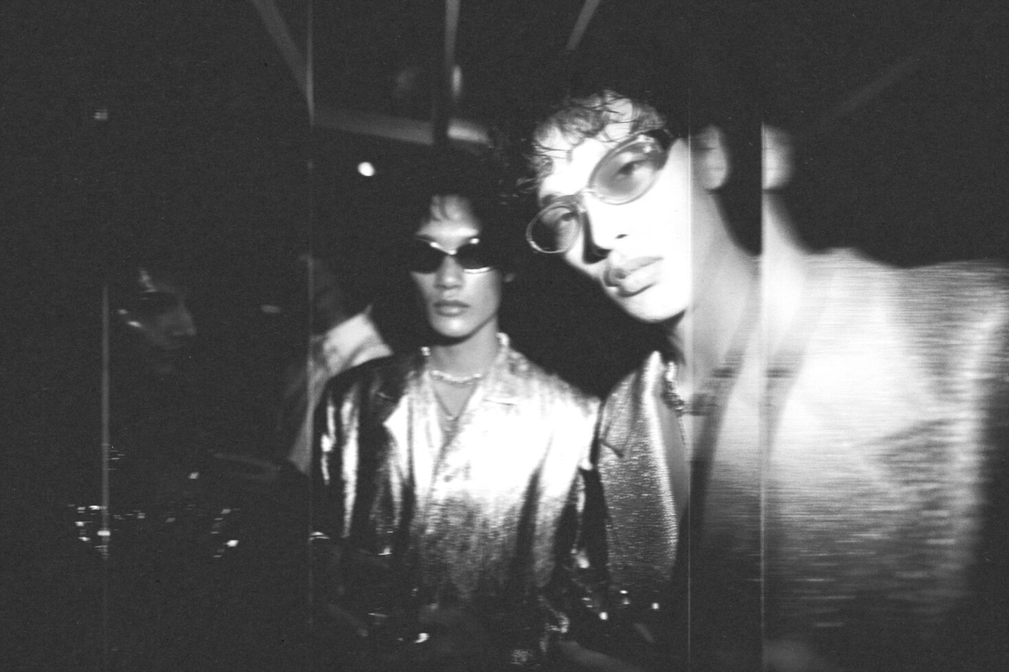 Grainy black white video footage of two people wearing sunglasses indoors