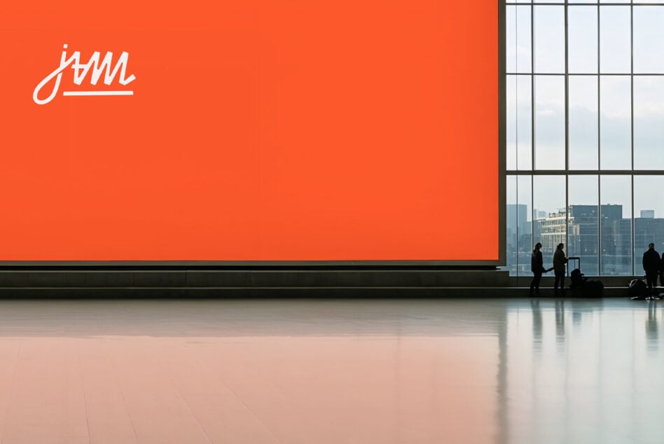 Bright orange billboard with handwritten logo inside modern office lobby with city views