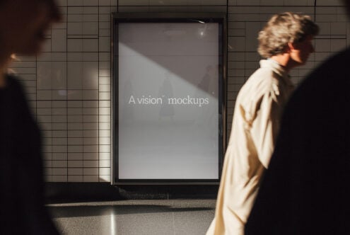 Blank grey screen mockup on subway wall with people walking by