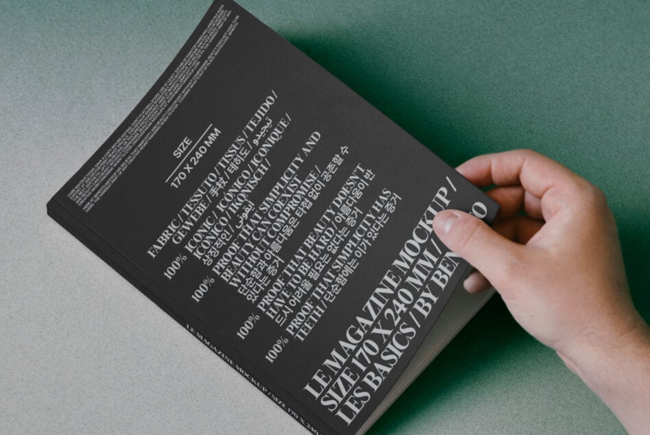 Hand holding dark book with multilingual text on green paper background, back cover