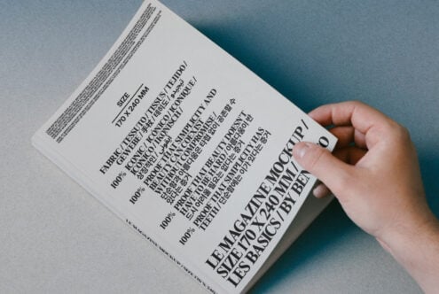 Magazine mockup template held by hand featuring multilingual text and modern typography design on a gradient background for graphic designers.