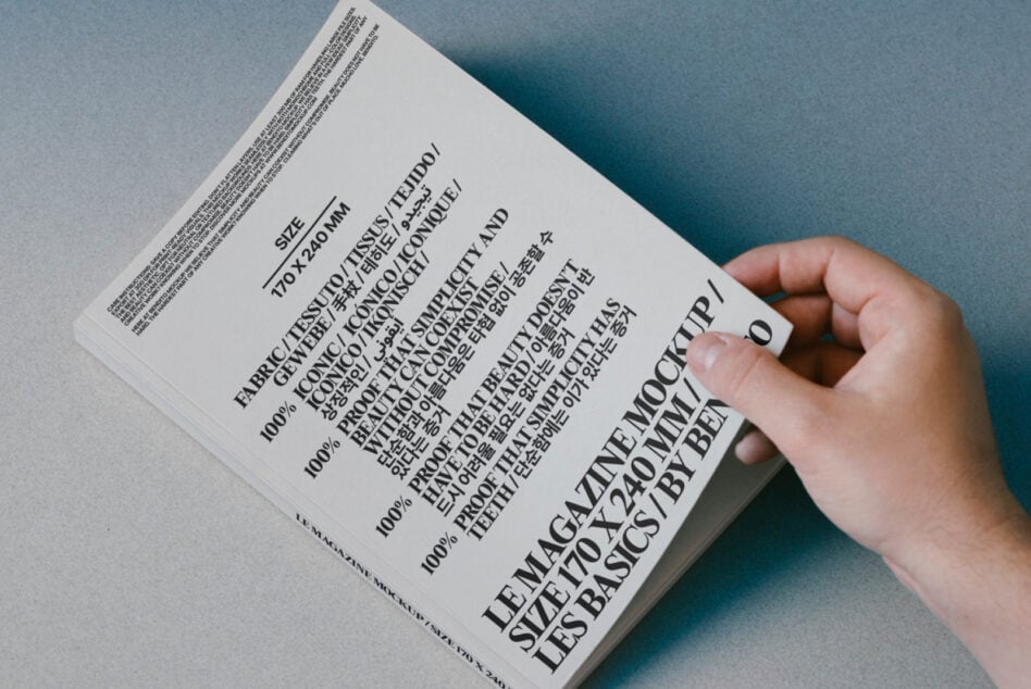 Hand holding white book with multilingual text on blue paper background, back cover