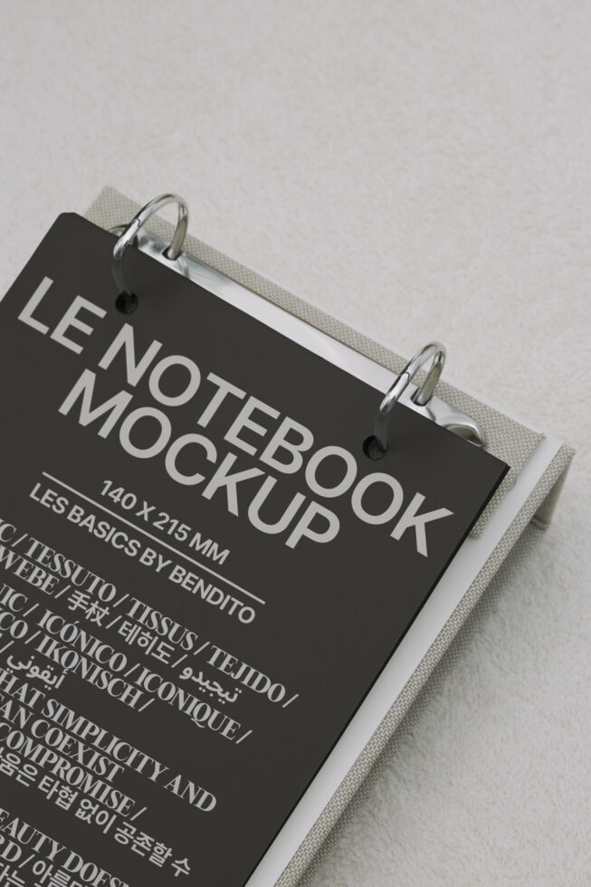 Black hardcover notebook with silver spiral binding on cream fabric backdrop