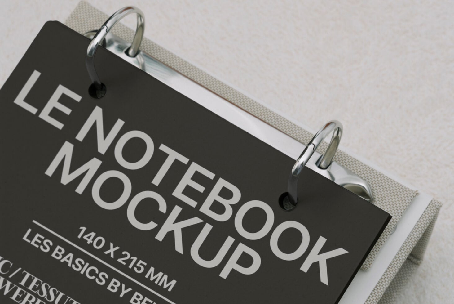 Black hardcover notebook clipped to cream fabric, angled view showing spine detail
