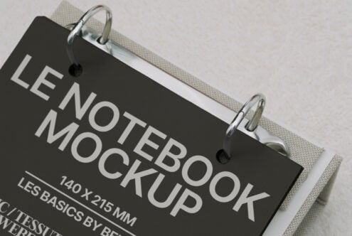 Black hardcover notebook clipped to cream fabric, angled view showing spine detail