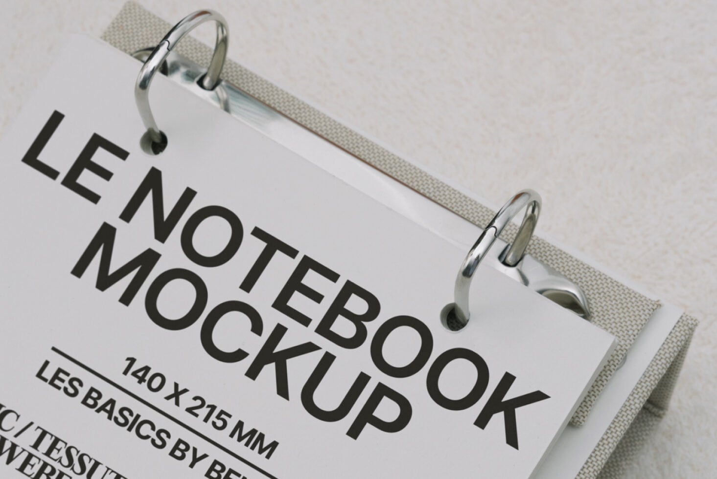 White hardcover notebook clipped to cream fabric, angled view showing spine detail