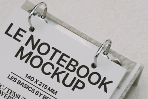 White hardcover notebook clipped to cream fabric, angled view showing spine detail
