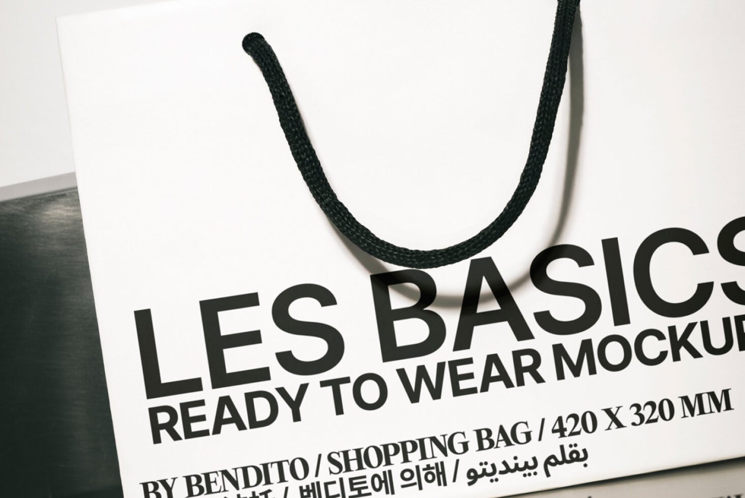 White shopping bag mockup with black rope handles tilted side angle view