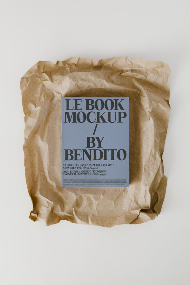 Book wrapped in crumpled kraft paper with blue label mockup