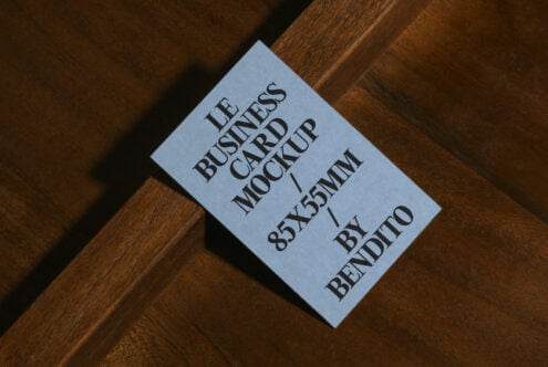 Periwinkle business card mockup on diagonal wood grain, serif typography, 85x55mm