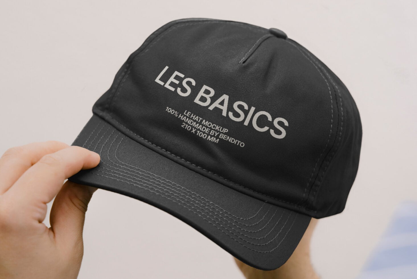 Black dad hat being held up showing Les Basics branding on crown