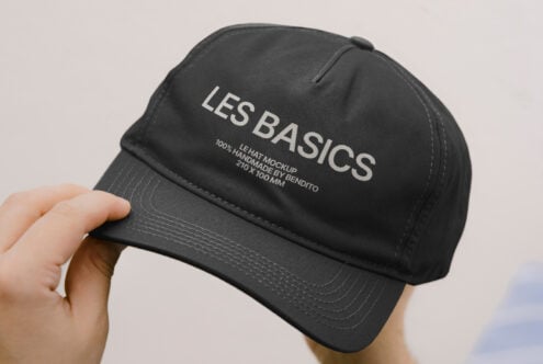 Black dad hat being held up showing Les Basics branding on crown