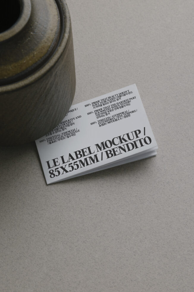 White business card stack beside textured pottery vessel on desk