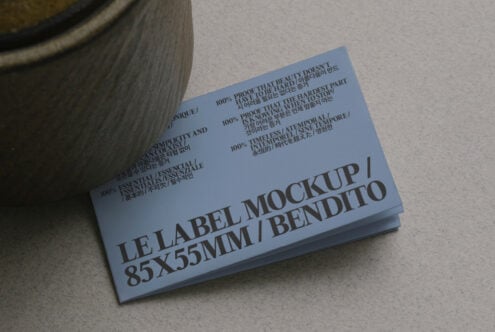 Blue business card mockup angled near ceramic planter with multilingual text