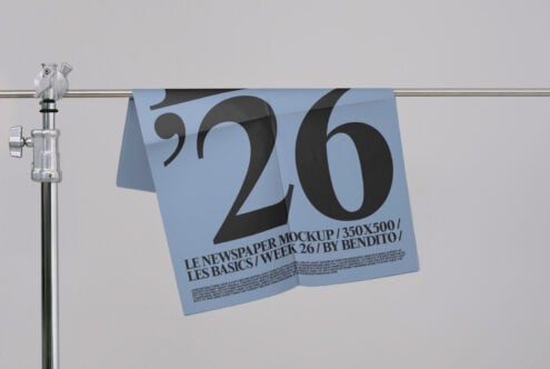 Blue newspaper mockup clipped on rod with bold '26' number design